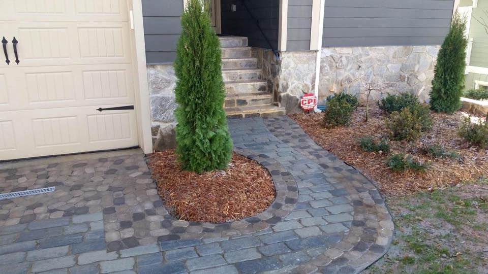 Curved stone paver walkway leading to home entrance stairs.