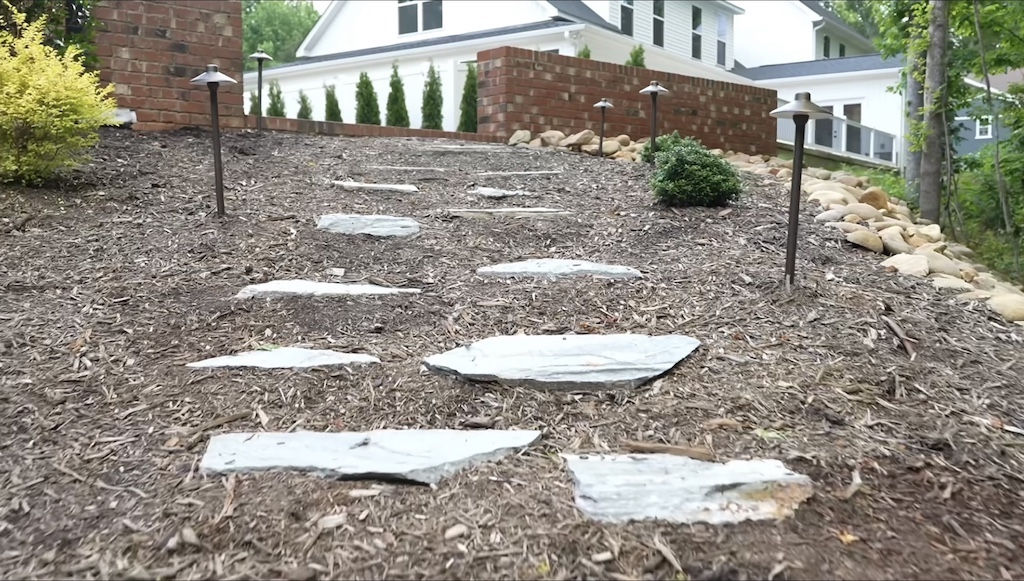 Flagstone stepping stones winding up a mulched slope.