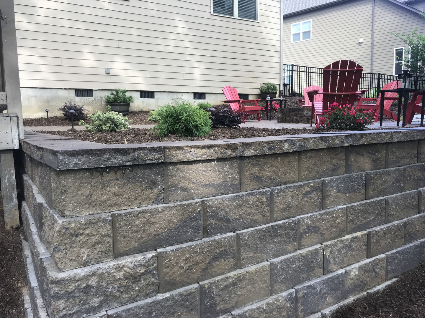 Stone retaining wall in a backyard patio area.